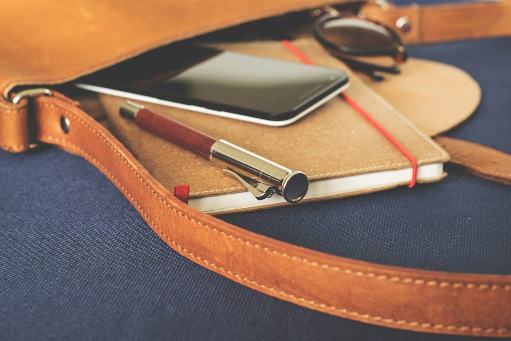 Notepad, phone, and pen in open leather bag