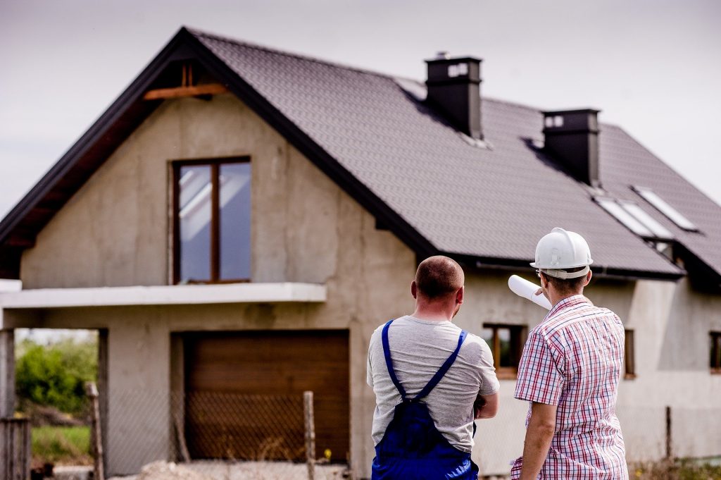 Two men with hard hats surveying house