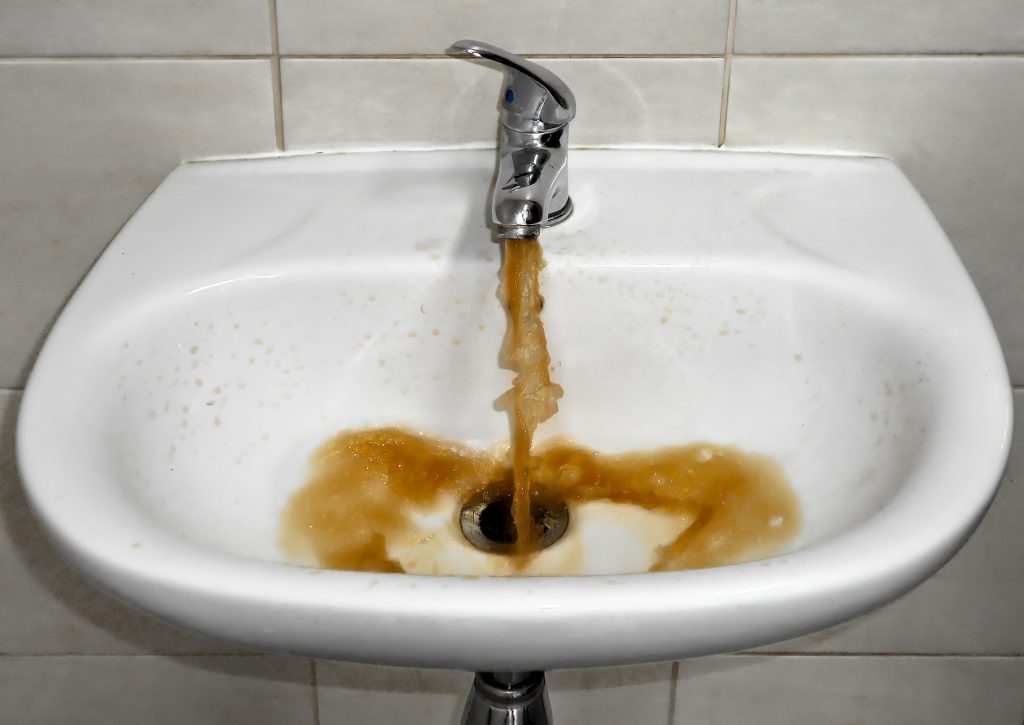 Tap spraying brown water into sink