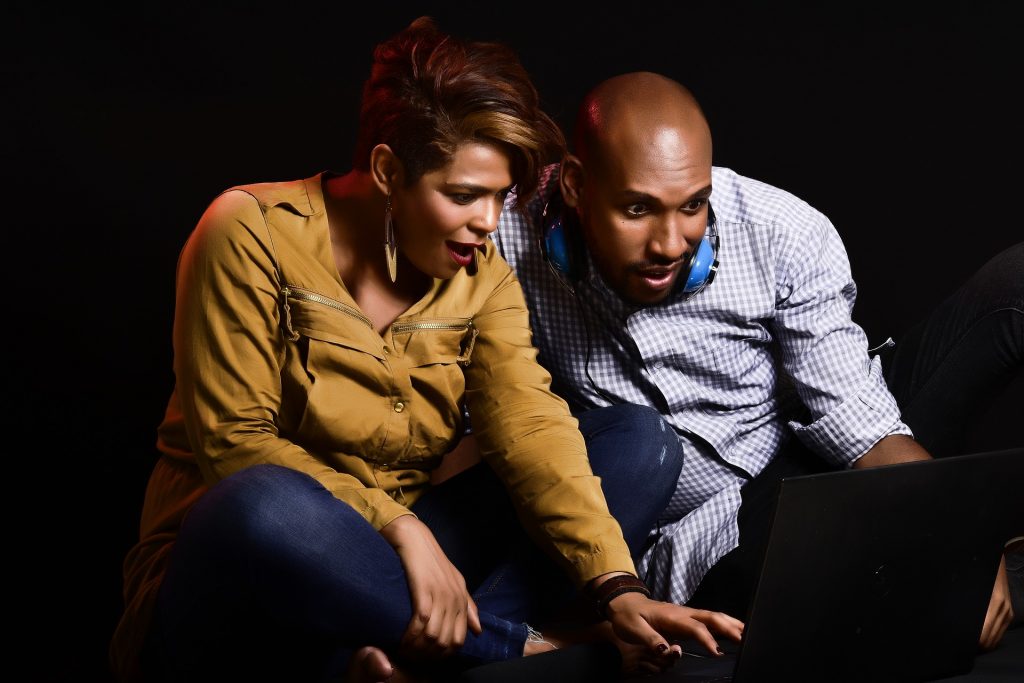 Black couple stare at laptop screen in smiling shock