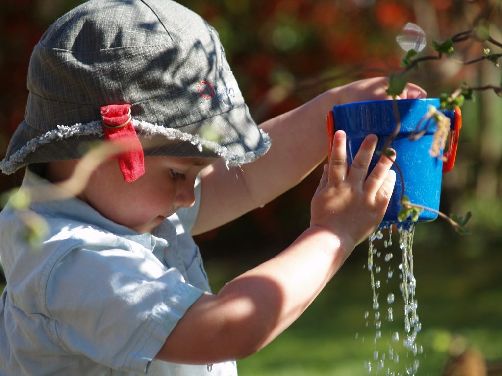Young boy holding plant pot as water flows out the bottom