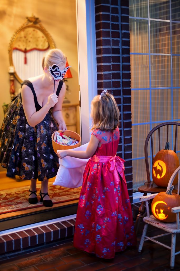 Young girl in princess dress trick or treating on doorstep