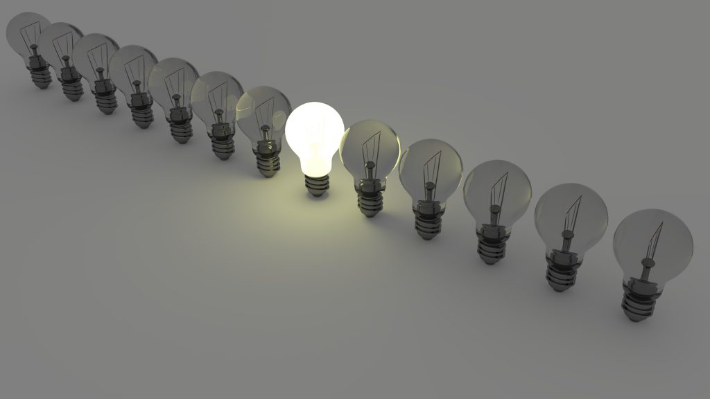 One illuminated lightbulb in a row of bulbs