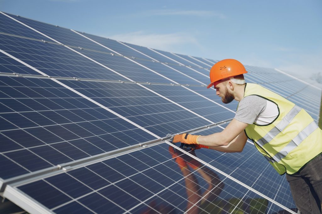 Man in hard hat fixing solar panels