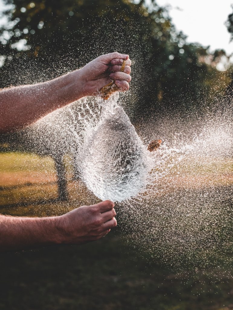 Hands popping water balloon