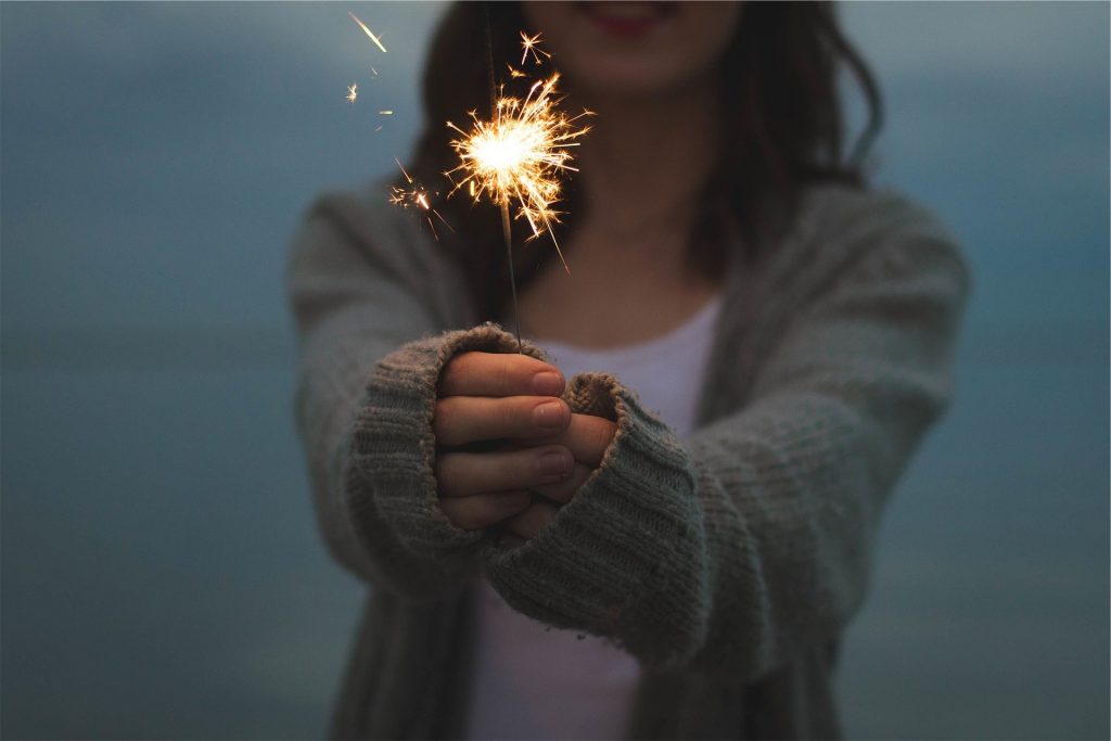 Woman in cardigan holding sparkler