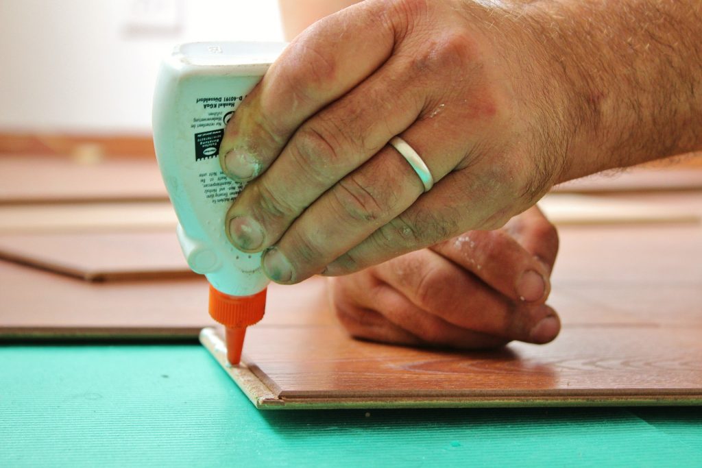 Hands gluing down wood flooring