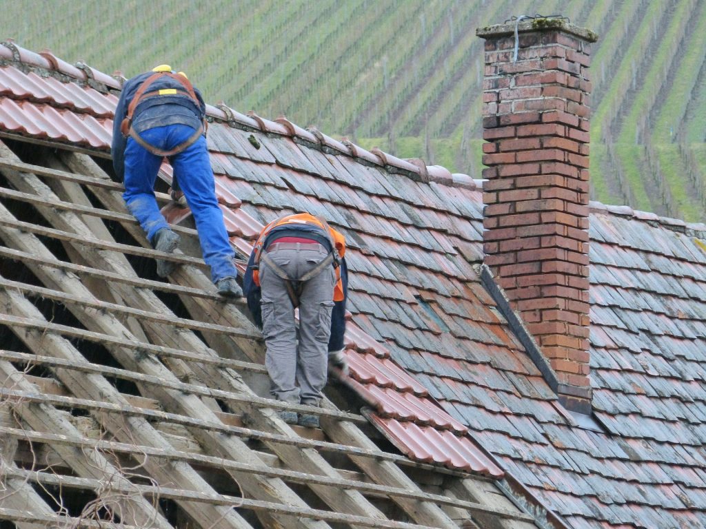 Men working to replace roof tiles