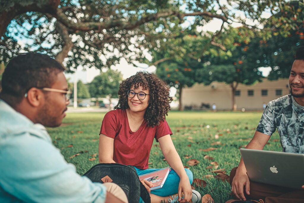 Three people sitting and talking on a lawn