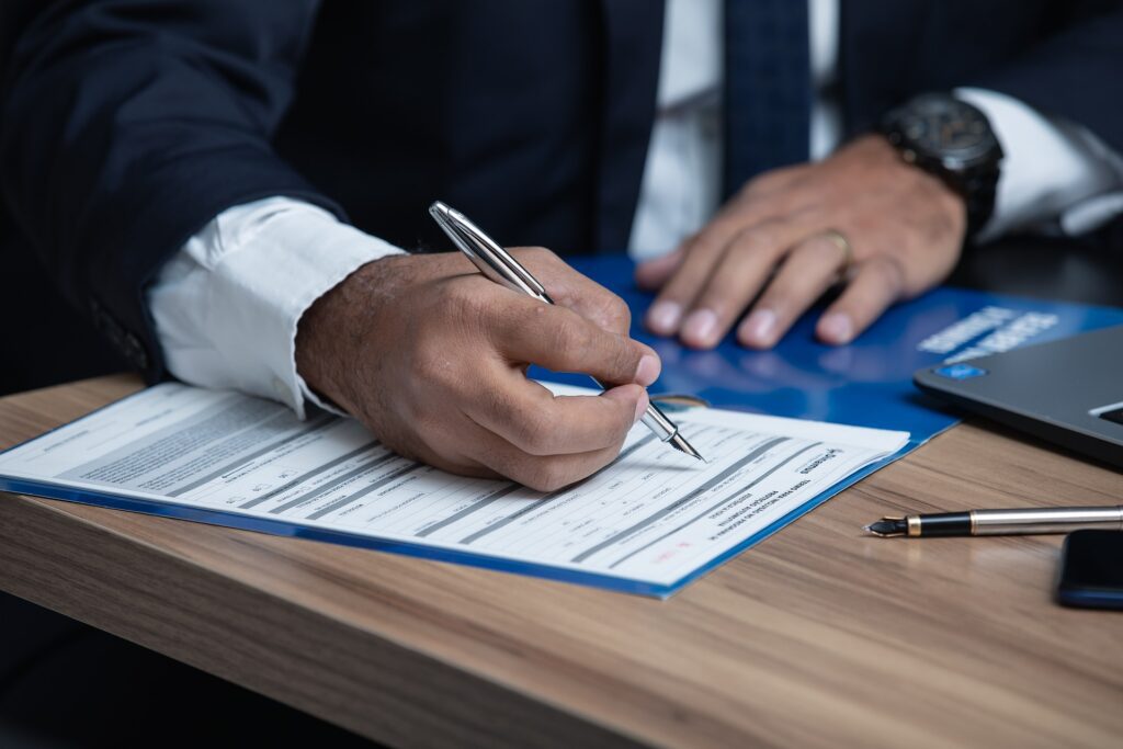 A man in a suit holding a pen about to write on paper